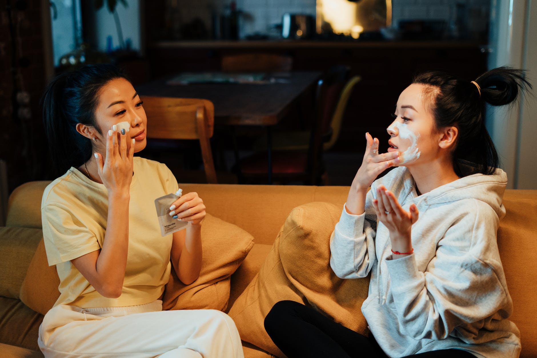 woman in white sweater and black pants sitting on brown couch