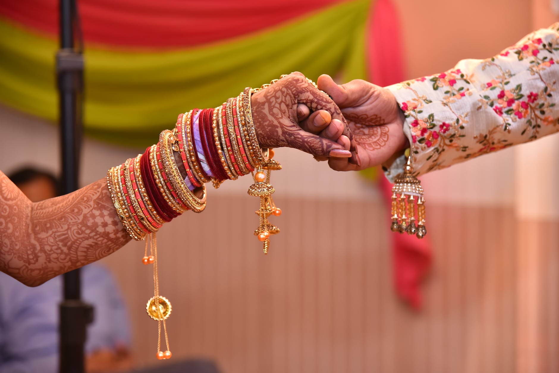 closeup of couples hands in traditional clothing and jewellery